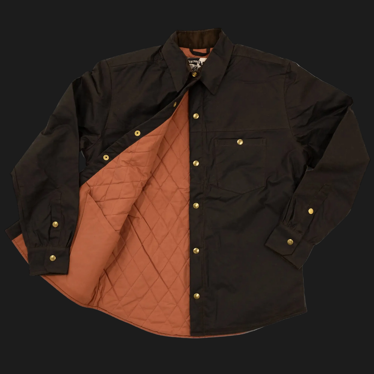 A black long-sleeve cold iron overshirt with a warm rust-orange quilted lining, shown open against a dark background. The shirt features brass-tone snap buttons and a chest pocket.