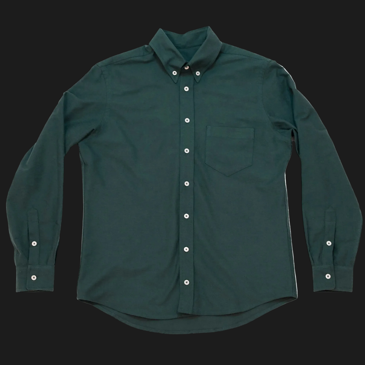 A dark green long-sleeve button-down shirt with a chest pocket and white buttons, laid flat against a dark background.