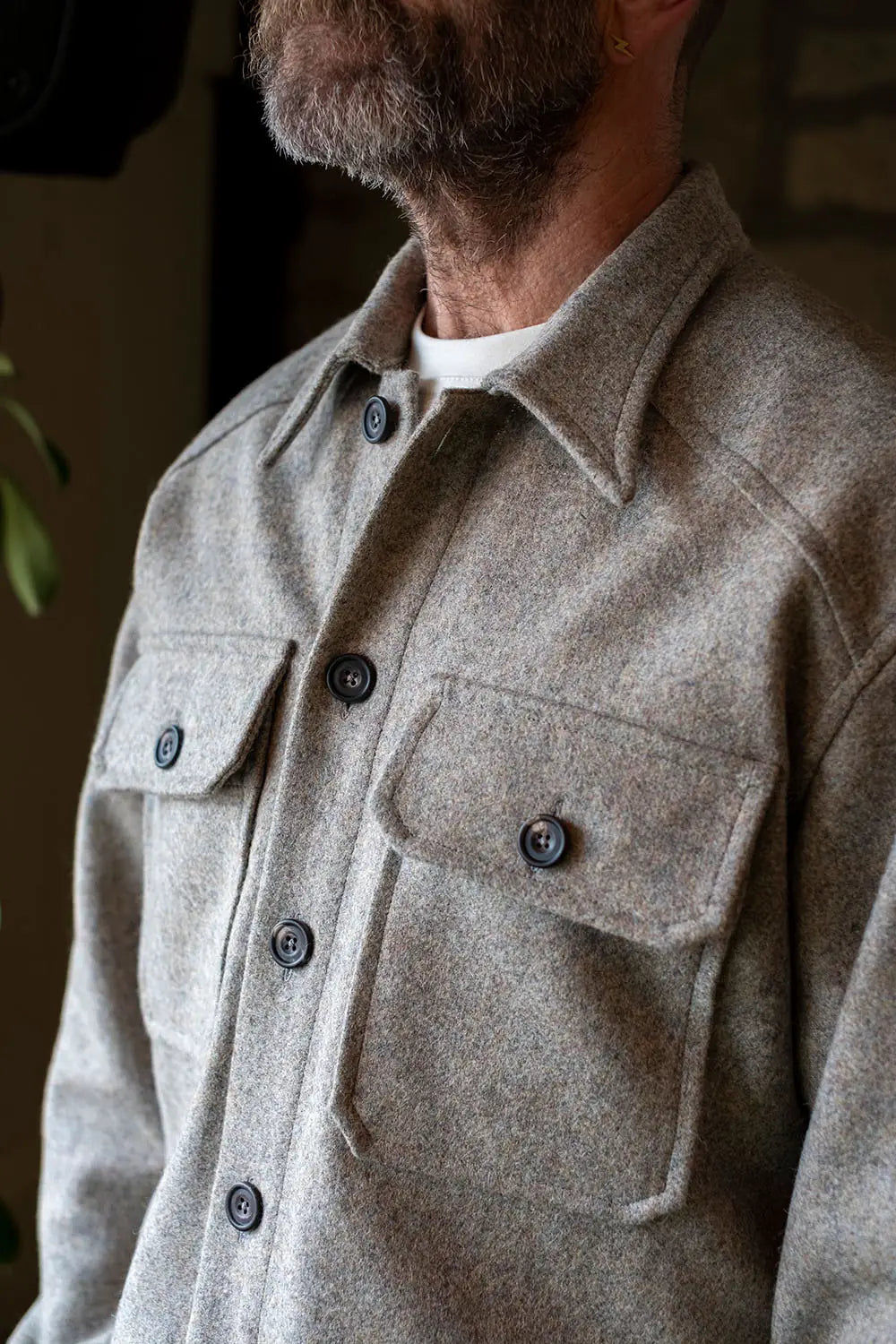 A close-up of a man wearing a USB37 wool overshirt jacket with dark buttons and two chest pockets.